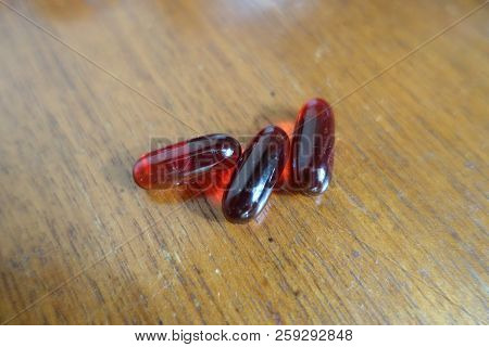 Red Capsules Of Krill Oil On Wood (three Items)