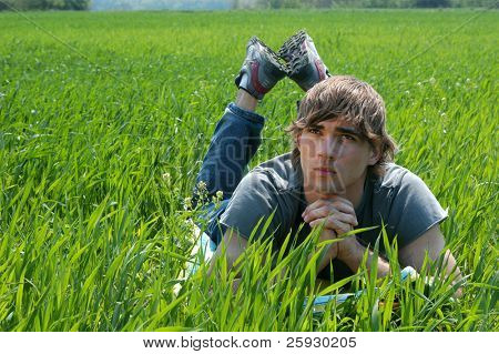 Giovane uomo posa sul prato verde.