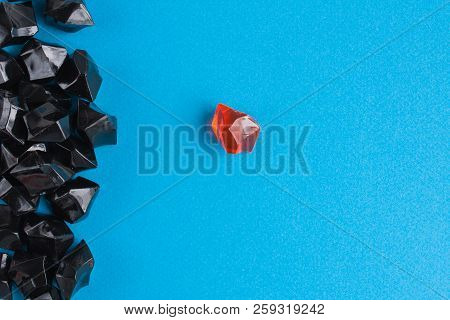 One Orange Plastic Gem Separately From The Rest On Blue Background