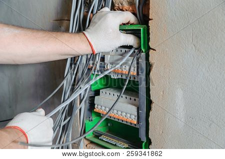 An Electrician Is Installing Electric Wires In A Switching Fuse Box.