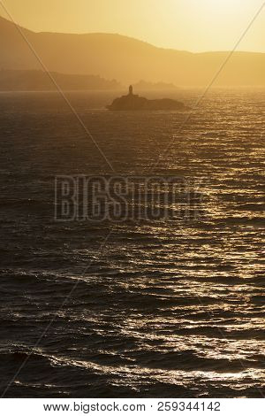 Lighthouse On Islet At Sunset Between Stormy Sea. Lighthouses Of Greece 