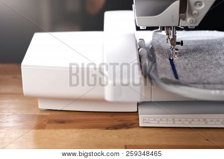 Modern Computerised Sewing Machine With Embroidery Unit Standing On A Warm Wooden Surface In Bright 