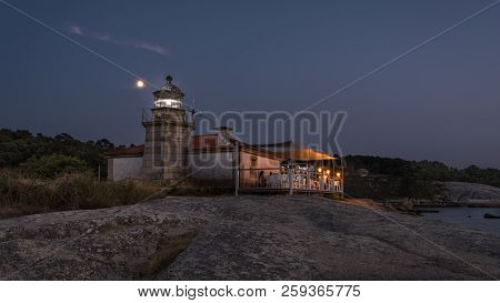 Illuminated Lighthouse Over The Sea And The Coast Of Galicia