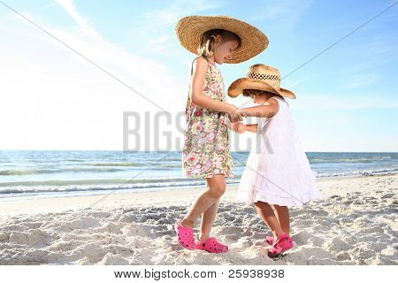 สองเล็กหญิงเต้นรำที่ชายหาดแดด ยิงเทียบกับดวงอาทิตย์