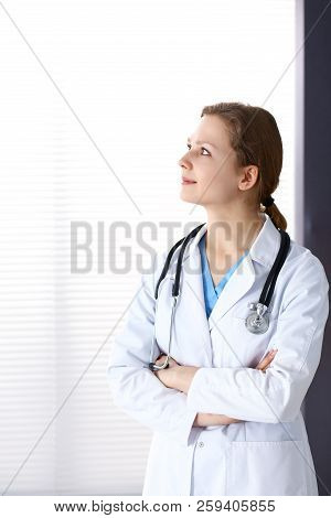 Woman Doctor With Crossed Arms Looking Up While Working In Hospital