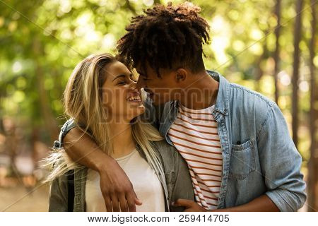 Lovely young multiethnic couple spending time together at the park, walking, hugging
