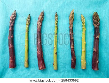 Background Flat Lay Green Purple Asparagus On Blue. Overhead.