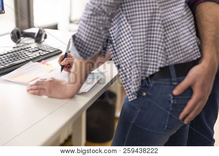 Businessman Sexualy Harassing Female Colleague During Working Hours At A Workplace. Focus On The Pen