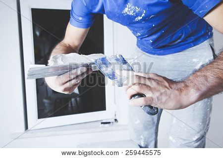 Scraper And Cement Filling For House Renovation Construction In Hands