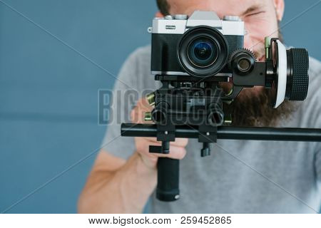 Video Content Creation Process. Man Looking Through Camera And Shooting Footage For Blog Or Broadcas