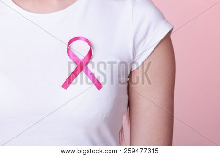 Healthcare, Medicine And Breast Cancer Awareness Concept - Closeup Of Pink Badge Ribbon On Woman Che