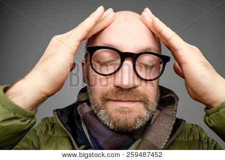 Portrait Of Bald Adult Man With Beard Toching His Head With Fingers. He Is Calm And Content