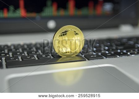 Golden Ripple Coin On A Black Keyboard Of Silver Laptop And Diagram Chart Graph On A Screen As A Bac