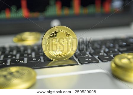 Golden Ripple Coin With Gold Coins Lying Around On A Black Keyboard Of Silver Laptop And Diagram Cha