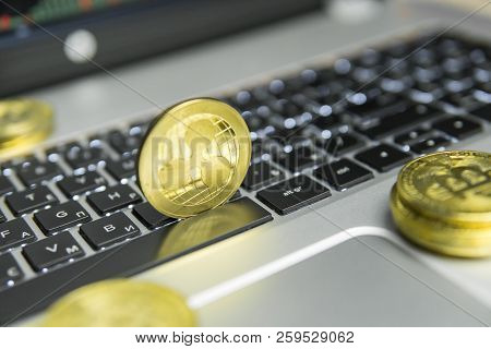 Golden Ripple Coin With Gold Coins Lying Around On A Black Keyboard Of Silver Laptop And Diagram Cha