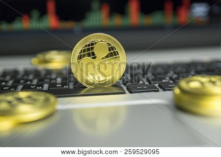 Golden Ripple Coin With Gold Coins Lying Around On A Black Keyboard Of Silver Laptop And Diagram Cha
