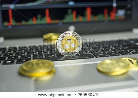 Golden And Silver Ripple Coin With Gold Coins Lying Around On A Black Keyboard Of Silver Laptop And 