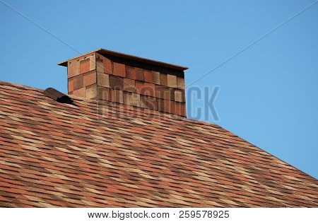 Part Of Brown Roof Of A House Covered With Soft Shingles With Short Big Smokestack Close Up Under Cl