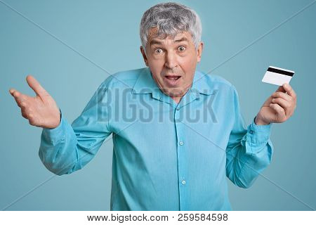 Puzzled Mature Wrinkled Man With Wrinkles On Face, Grey Hair, Shrugs Shoulders In Bewilderment, Does