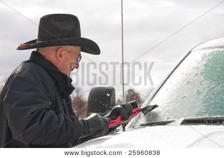 Mann mittleren Alters kratzen Eis von seinem LKW Windschutzscheibe nach einem Eissturm