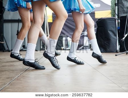Female Legs Of Three Irish Dancers In Blue Dresses On The Stage Closeup