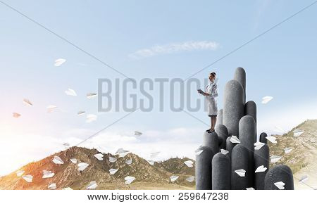 Young Female Doctor With Folder In Hands Satnding On Stone Column
