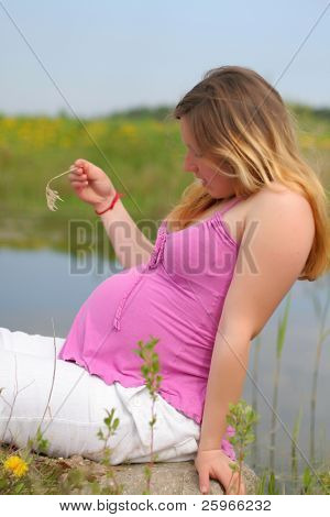 Молодой беременной женщины в сельской местности сидит и ждать своего ребенка