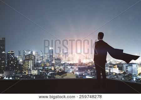 Young Backlit Super Hero Businessman On Rooftop With Night City View. Leadership And Confidence Conc