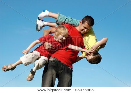 O pai brincando com filhos contra o céu