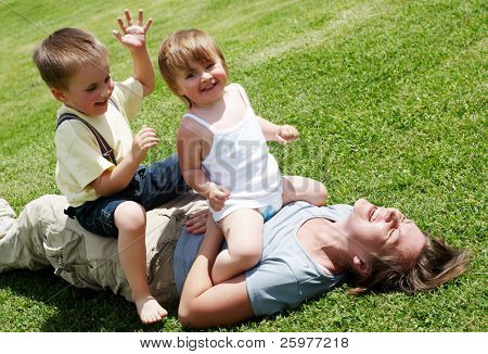 Heureuse mère jouant avec les enfants sur la pelouse