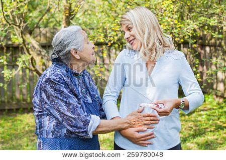 Happy Woman Expecting A Baby, Holding Pregnancy Test, Spending Time With Future Great-grandmother