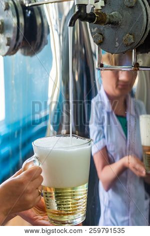 Pouring Sparkling Wine In Glass Jug At Winery.