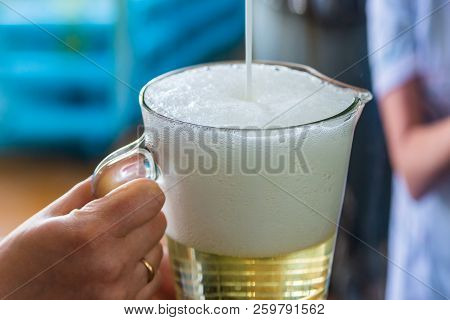 Pouring Sparkling Wine In Glass Jug At Winery.