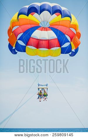 Couple Of Tourists Flying On A Colorful Parachute