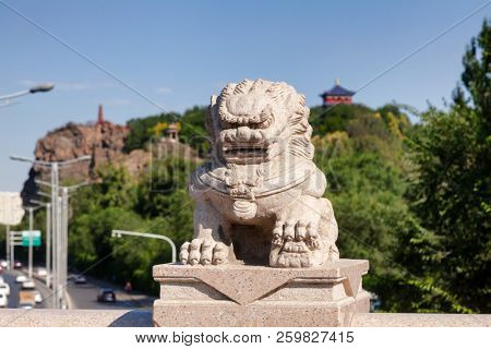 Stone lion on Xi Daqiao Bridge with Hong Shan (Hongshan or Red Mountain) Park seen in background, Urumqi, Xinjiang, China
