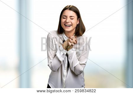 Young Woman Bursting In Laugh. Pretty Girl Is Laughing With Closed Eyes And Clasped Hands. Human Exp