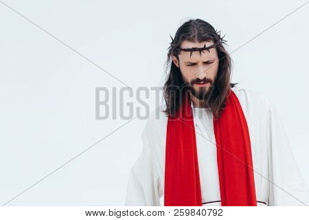 Jesus In Robe, Red Sash And Crown Of Thorns Looking Down Against Light Sky