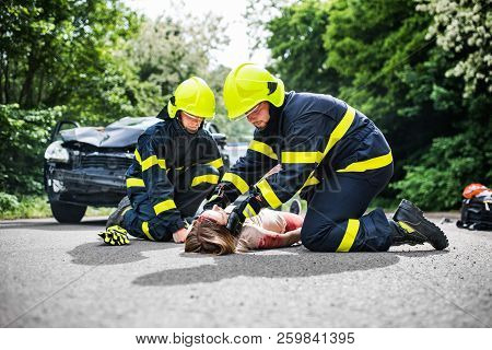 Firefighters Helping A Young Injured Woman After A Car Accident.
