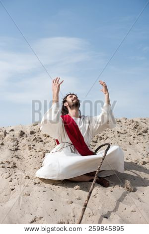 Cheerful Jesus In Robe And Red Sash Sitting In Lotus Position With Raised Hands And Talking With God