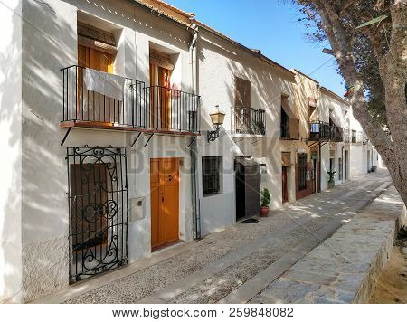 Charming Narrow Street In Island Of Tabarca. White Residential Typical Houses, Narrow Pebble Walkway