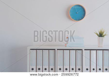 Modern Bright Business Office Interior Detail Depicting Wall Clock And Shelf With Books, Plant And F