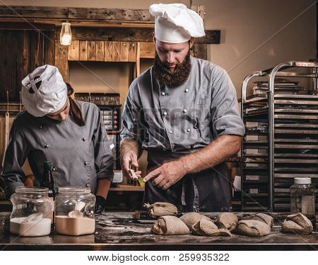 Chef Teaching His Assistant To Bake The Bread In A Bakery.