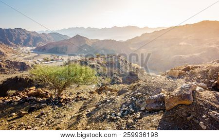 Scenic overlook of Al Hajar mountains in the emirate of Fujeirah, UAE and a village in a valley
