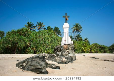 Croce di rocky contro il cielo blu sulla spiaggia di Morjim in Goa, India