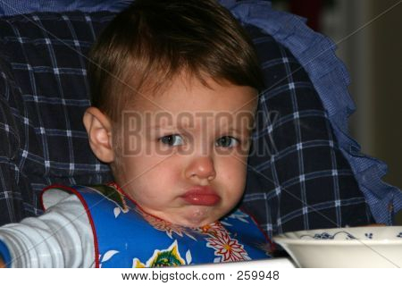 Niño en la silla alta haciendo una cara haciendo pucheros