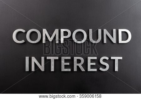 The Words Compound Interest Laid With Silver Metal Letters On Matte Black Surface In Flat Lay Compos