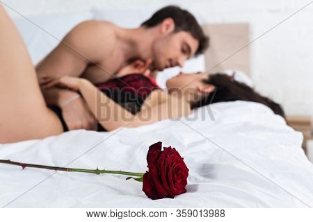 Selective Focus Of Red Rose Near Passionate Couple Hugging On Bed