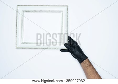 A Man Hand With Black Gloves Holding A Empty(blank) White Photo Frame Isolated On White Background.