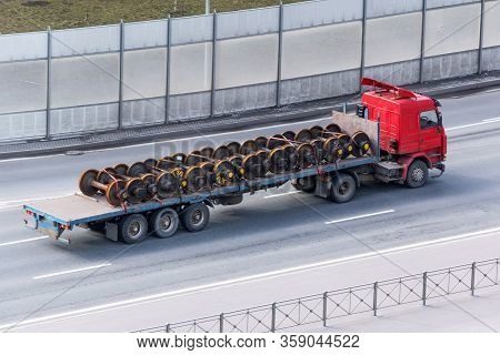 Commercial Delivery Cargo Truck With Open Trailer Driving On The Highway, Loaded With Wheelsets From