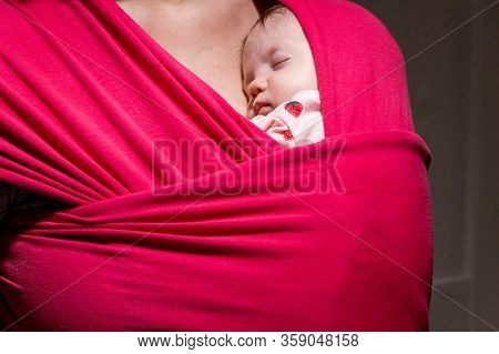 Mother Carrying Her Cute Baby Daughter In Sling. Newborn Baby Sleeping In A Sling, In The Embrace Of